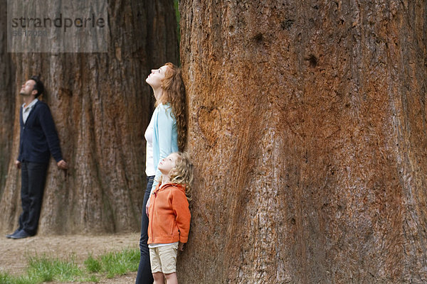Mutter und Tochter lehnen sich an den Baumstamm und atmen frische Luft.