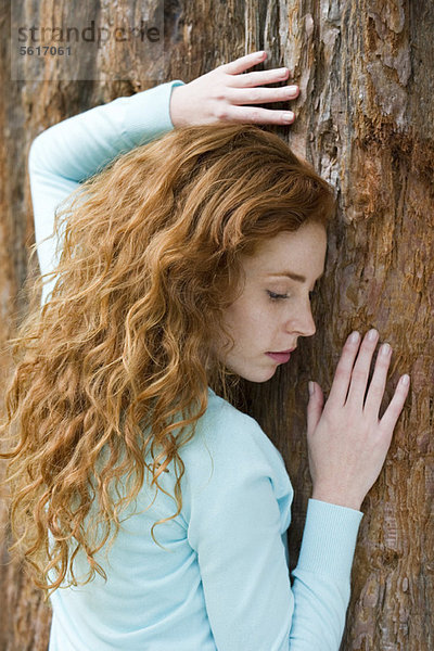 Junge Frau berührt Baum  Portrait