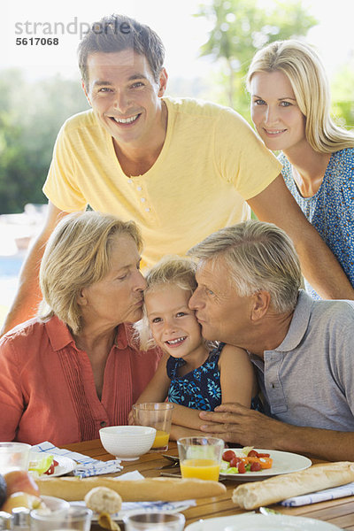 Familie beim Frühstück im Freien  Großeltern küssen die Wangen der Enkelin  Porträt