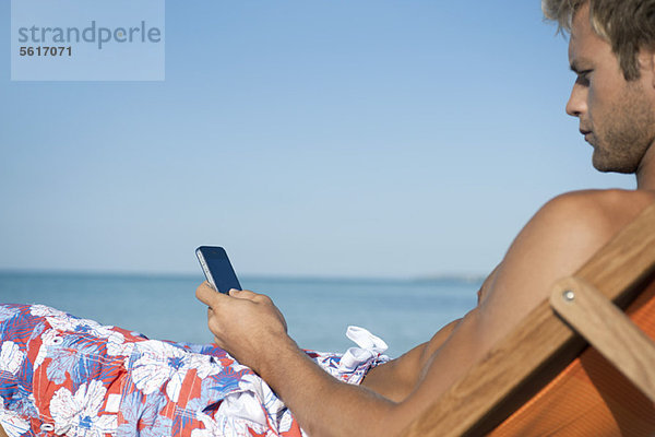 Junger Mann SMS am Strand