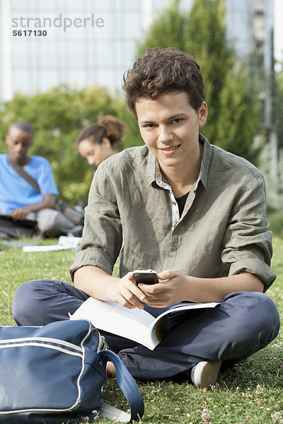 Junger Mann mit Handy  Freunde im Hintergrund  Portrait