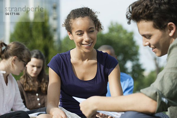 Studenten  die gemeinsam im Freien studieren  konzentrieren sich auf eine Frau.