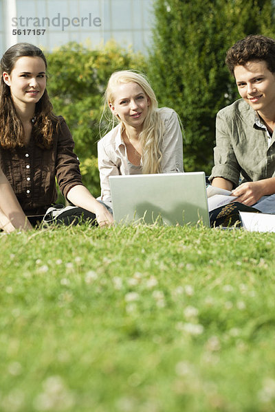 Universitätsstudenten  die gemeinsam auf Rasen studieren  Blickwinkel niedrig