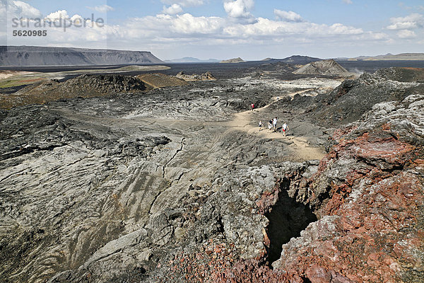 Besucher wandern durch die Landschaft voller Lavafelder  farbiger Lava und erloschener Krater im Geothermalgebiet der Leirhnjukur-Spalte am Vulkan Krafla im Norden von Island  Europa