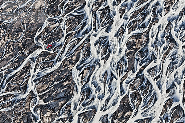 Luftaufnahme  ein einmotoriges rotes Leichtflugzeug über den verzweigten Fließstrukturen  Flussstrukturen des Schmelzwassers  das aus dem Gletscher Vatnajökull in die weite Sandebene des Skeithararsandur  Skei_ar·rsandur  austritt  Island  Europa