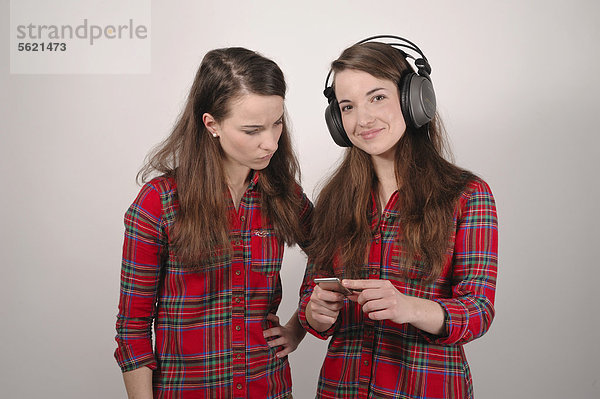 Zwillingsschwestern  die eine hält einen iPod  die andere mit Kopfhörern