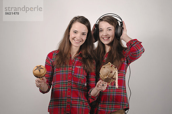 Zwillingsschwestern  die eine musiziert mit Rasseln  die andere hört mit Kopfhörern