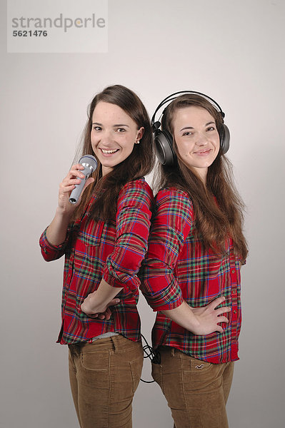 Zwillingsschwestern  die eine singt in ein Mikrofon  die andere hört mit Kopfhörern
