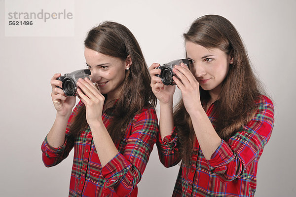 Zwillingsschwestern mit Digitalkameras