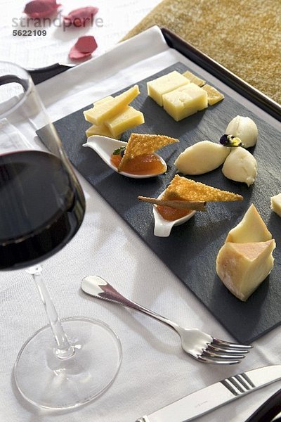 Tablett mit Appetizers (Käse und Marmelade) und ein Glas Rotwein