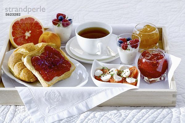 Frühstück im Bett mit Tee  Marmelade  Joghurt  Obst und Tomaten mit Mozzarella