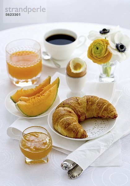 Frühstück mit Melone  Croissant  Ei  Marmelade  Kaffee und Orangensaft