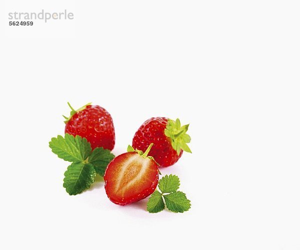 Erdbeeren mit Blättern vor weissem Hintergrund