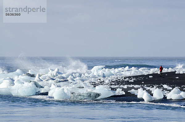 Tourist  Eisberge und Eiskristalle am schwarzen Strand  Jökuls·rlÛn  Vatnajökull Gletscher  Austurland  Ost-Island  Island  Europa