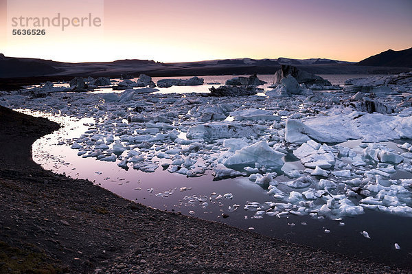 Blaue und von Asche schwarz gefärbte Eisberge und Eiskristalle im Abendlicht  Gletscherlagune Jökuls·rlÛn  Vatnajökull Gletscher  Austurland  Ost-Island  Island  Europa