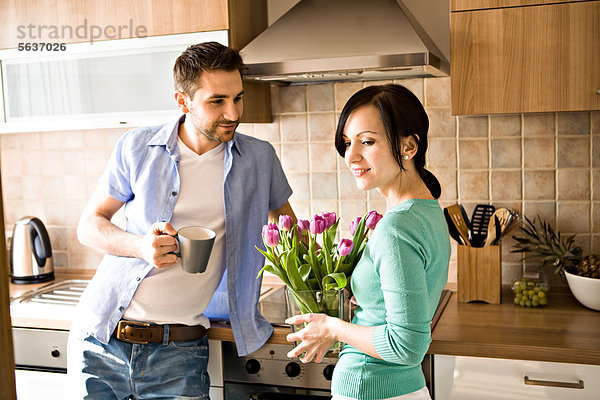 Junges Paar mit einem Strauß Tulpen in der Küche