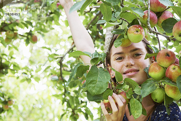 Lächelndes Mädchen spielt im Obstbaum