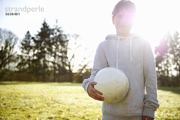 Junge mit Fußball auf der Wiese