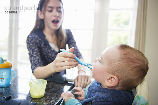 Mädchen füttern Baby-Bruder am Tisch