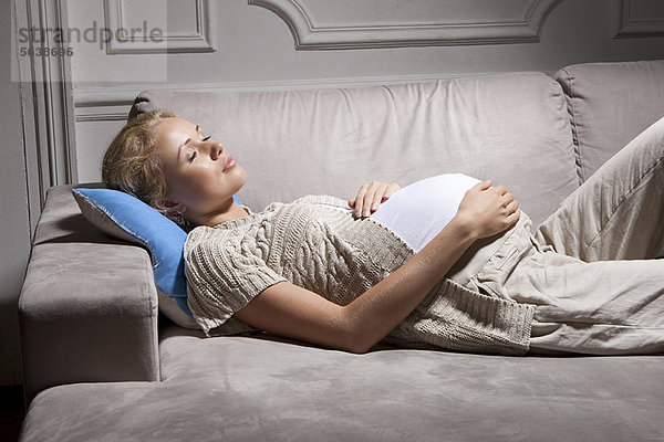 Schwangere Frau schläft auf dem Sofa