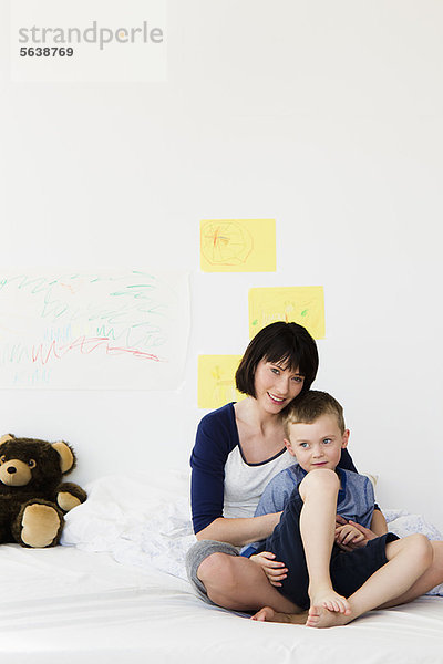 Mutter und Sohn auf dem Bett sitzend