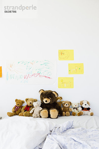Teddybären und Kinderzeichnungen auf dem Bett