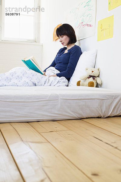 Frau liest Buch im Bett