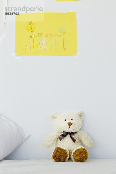 Teddybär und Kinder zeichnen auf dem Bett