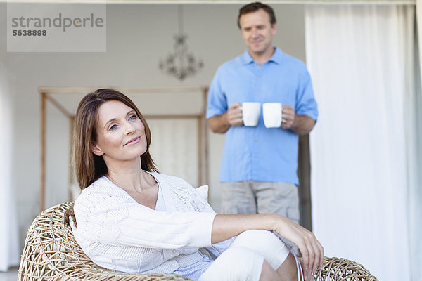 Mann bringt Freundin Kaffee auf die Veranda