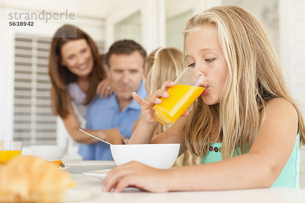 Mädchen trinkt Orangensaft beim Frühstück