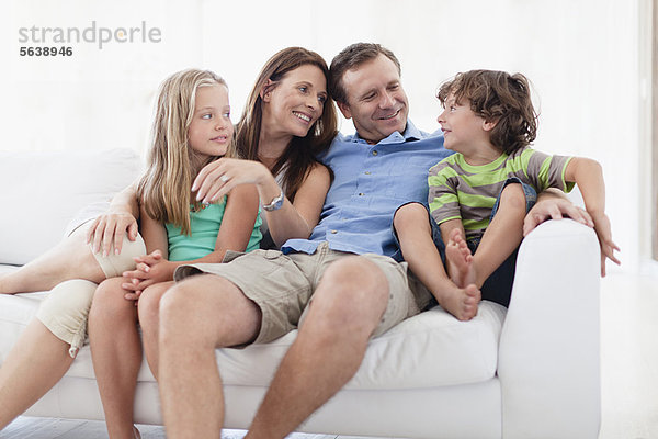 Familie entspannt gemeinsam auf dem Sofa