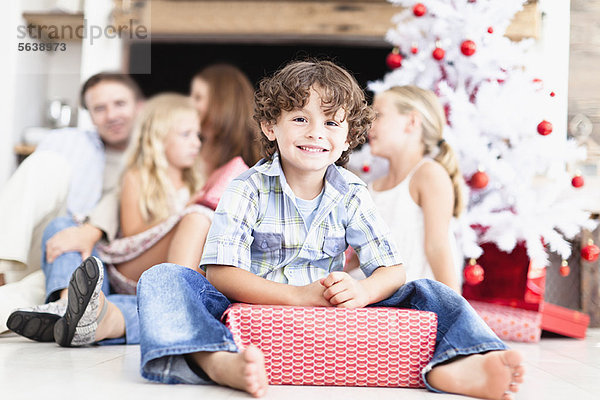 Junge sitzend mit verpacktem Weihnachtsgeschenk