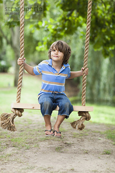 Lächelnder Junge in Baumschaukel sitzend