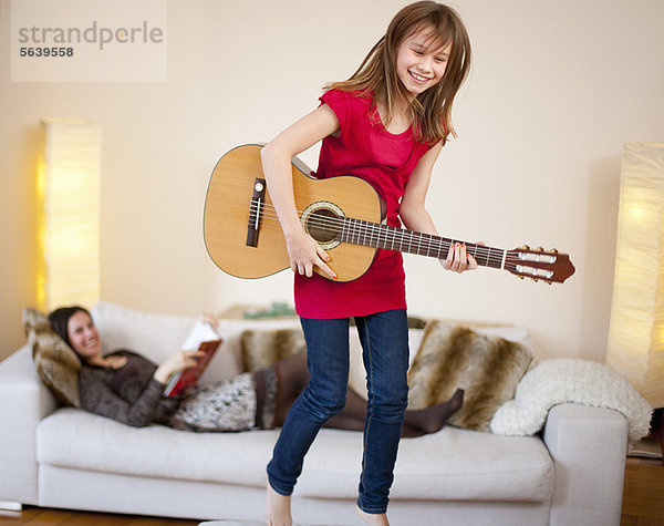 Mädchen spielt Gitarre im Wohnzimmer