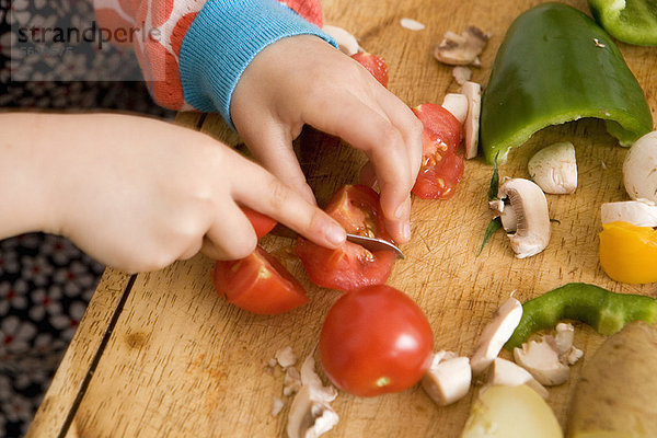 Nahaufnahme des Kindes beim Schneiden von Gemüse