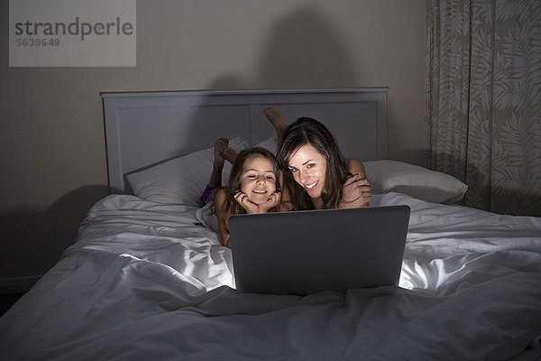 Mutter und Tochter mit Laptop im Bett