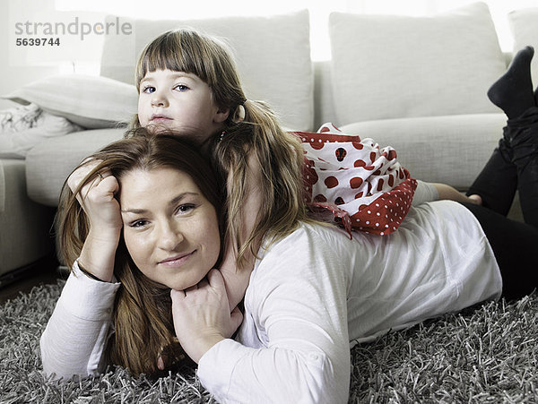 Mutter und Tochter liegen auf einem Teppich