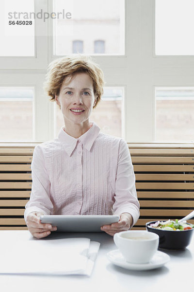 Eine Geschäftsfrau  die in der Mittagspause ein digitales Tablett benutzt.