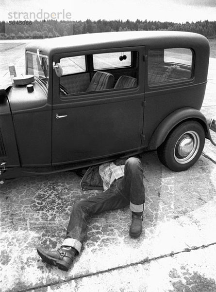 Ein Mann  der ein altes Auto repariert.