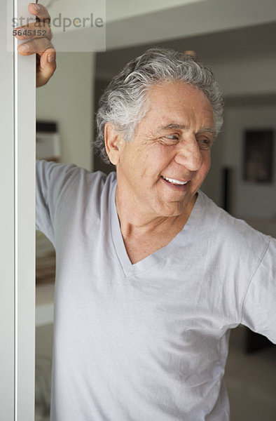 Ein fröhlicher  älterer Mann steht in einer Tür.