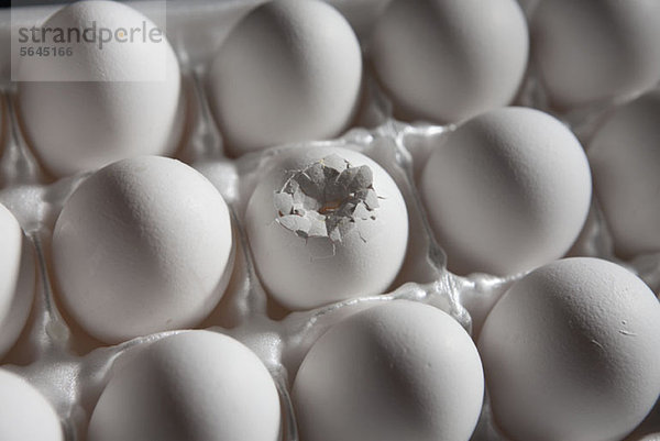 Ein zerbrochenes Ei unter den Eiern im Karton