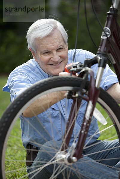 Ein älterer Mann  der ein Fahrrad repariert.