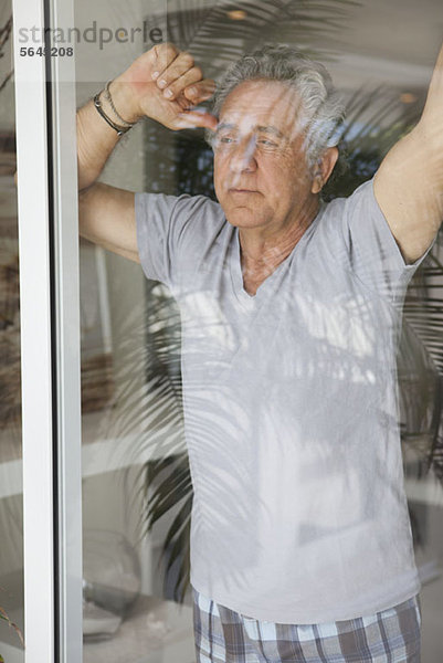 Ein älterer Mann  der aus dem Fenster schaut.
