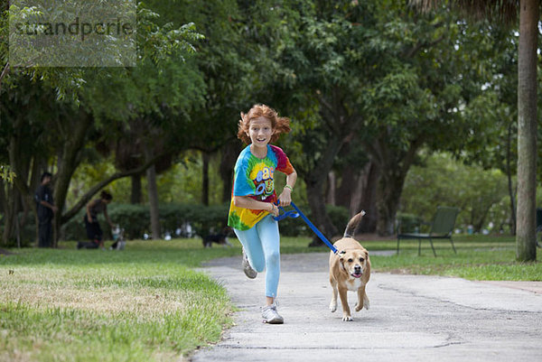 Mädchen läuft mit Hund durch den Park