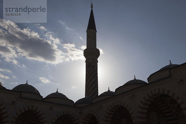 Das Minarett einer von der Sonne hinterleuchteten Moschee