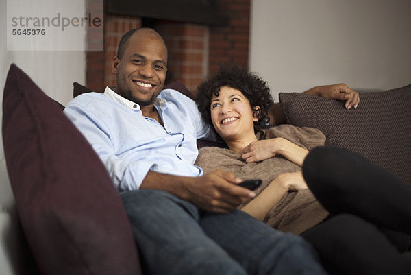 Ein fröhliches  lachendes Paar  das zusammen auf einem Sofa sitzt.