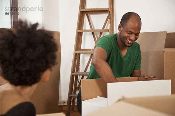 A couple packing moving boxes  focus on man