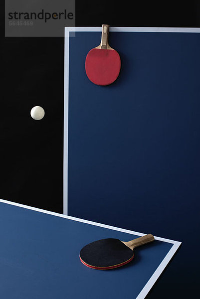 Table tennis tables  bats and a ball mid-air
