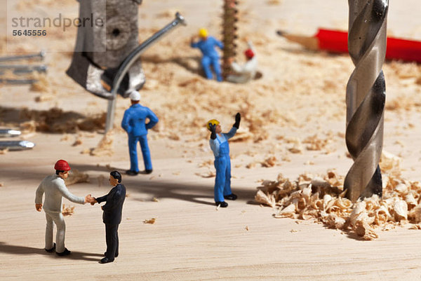 Ein Diorama einer Miniaturbaustelle  Vorarbeiter beim Händeschütteln mit Geschäftsmann