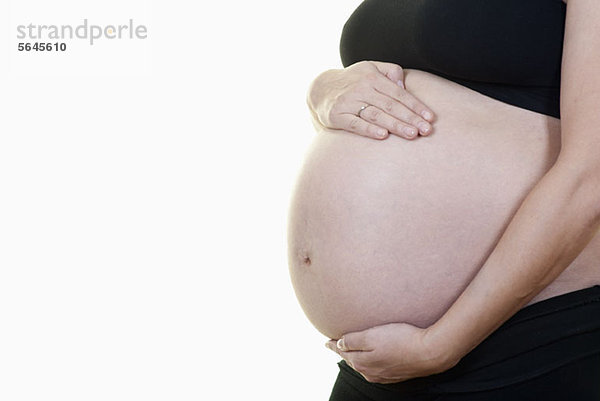 Eine schwangere Frau hält ihren Bauch  Mittelteil  Seitenansicht